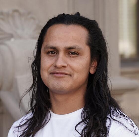 Luis Martinez in a white polo shirt with long, black hair