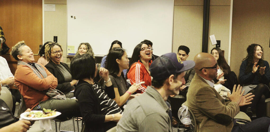 Staff, allies, students sitting in a room laughing and smiling