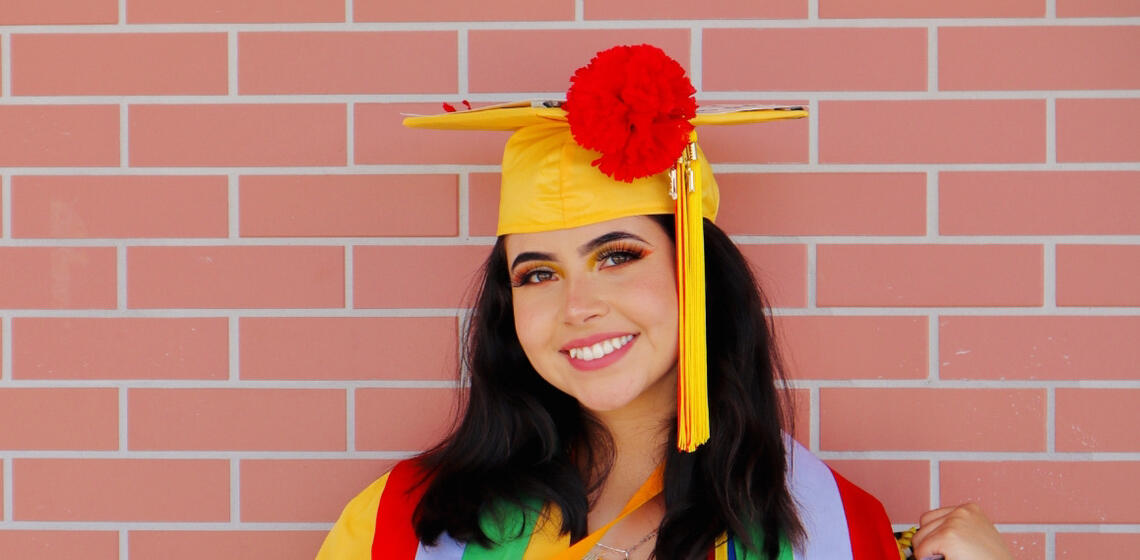 Picture of Kimberly Cardenas in yellow graduation cap and gown